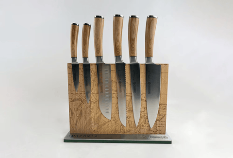 Set of knives with wooden handles on a decorative stand against a white background
